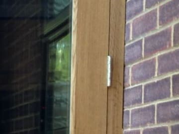 Hinge on the frame of an oak French door set in brickwork
