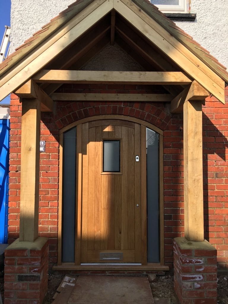 Oak framed porch over an arched oak front door with glazed sidelights