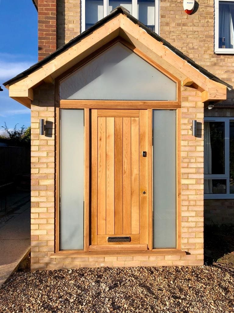Boarded oak front door with frosted sidelights under a timber porch