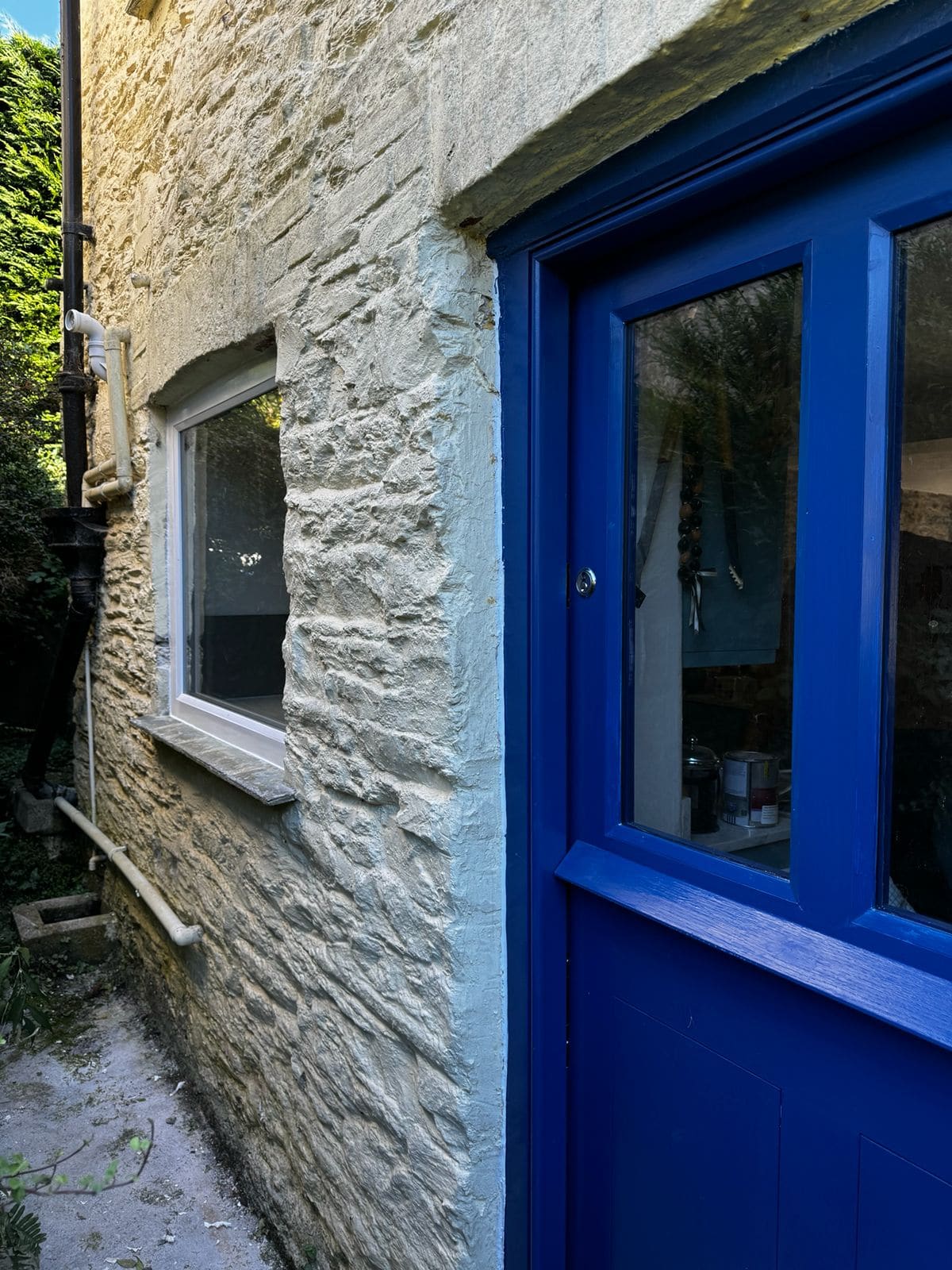 Blue painted stable door set into a limewashed stone wall