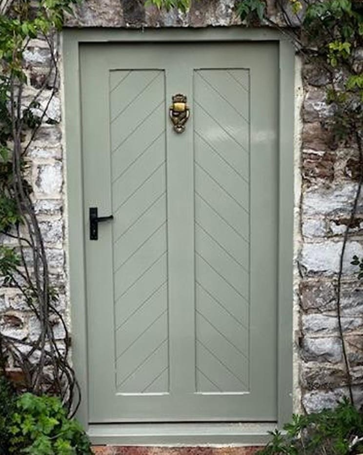 Sage green ledged front door set in an old stone wall