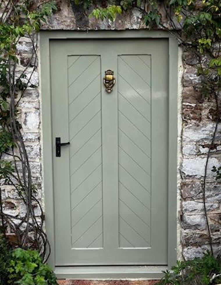 Sage green ledged front door set in an old stone wall