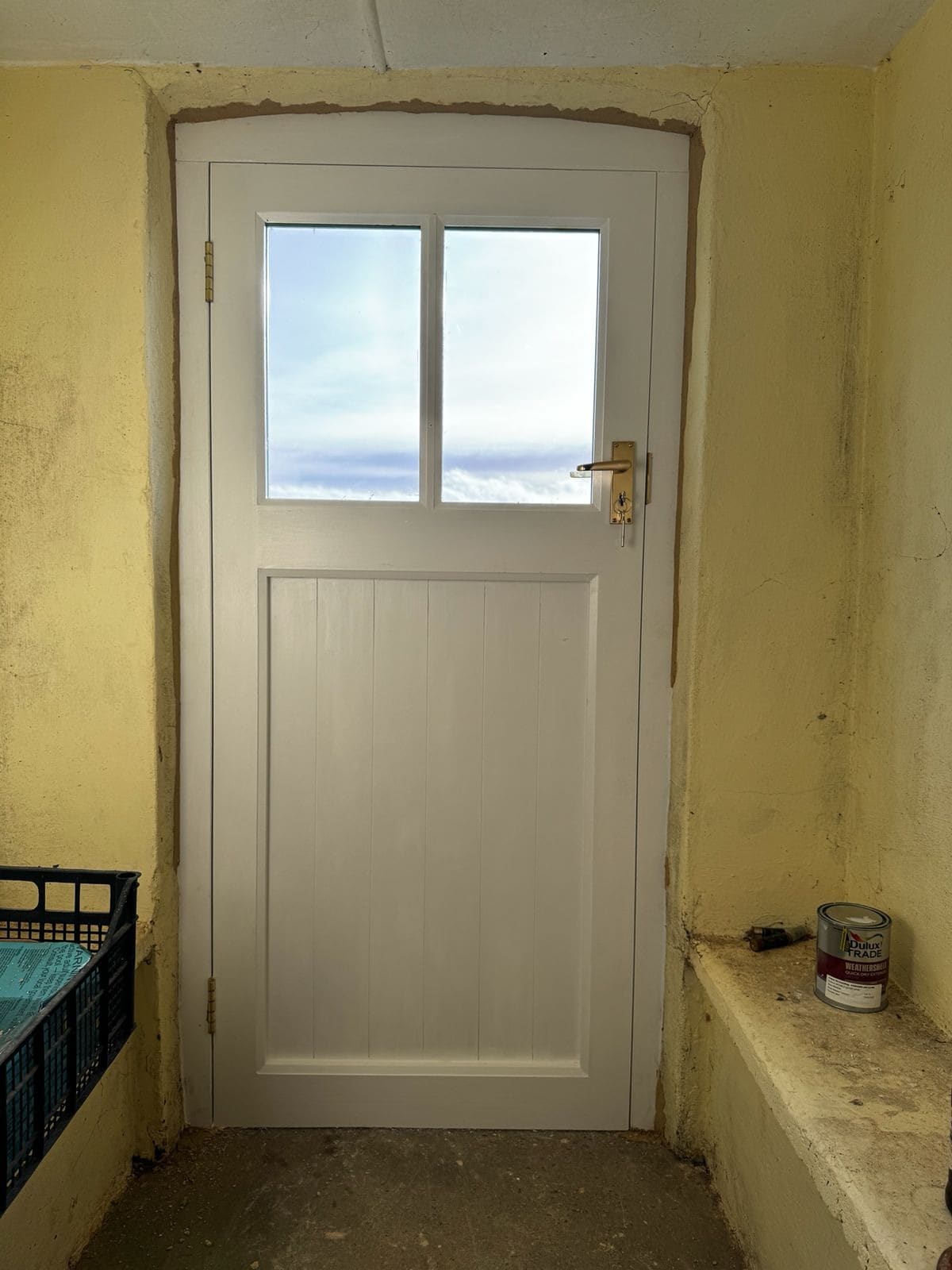 White painted framed door fitted into a thick, uneven cottage wall