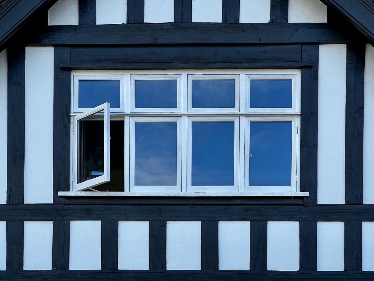 White timber casement windows with an opening light in a black and white timber-framed gable