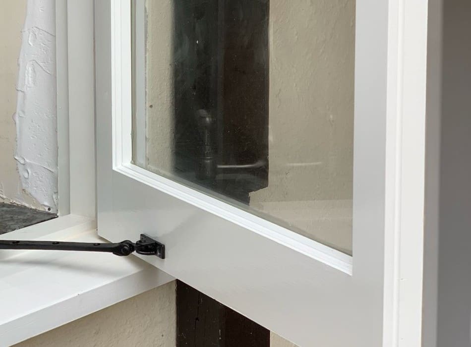 Black monkey-tail casement stay and fastener on a white painted timber window