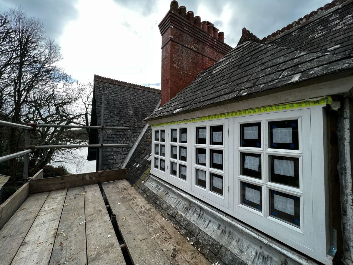 New white timber casement windows fitted along a dormer on a slate roof
